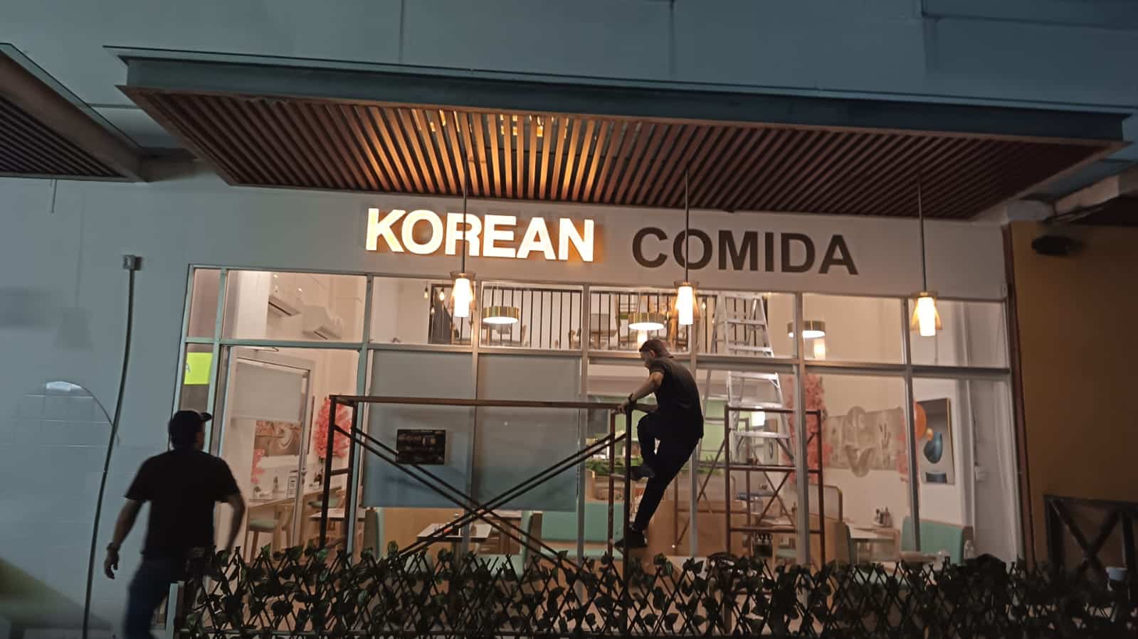 Instalación nocturna de letrero luminoso para restaurante en Cancún con andamios